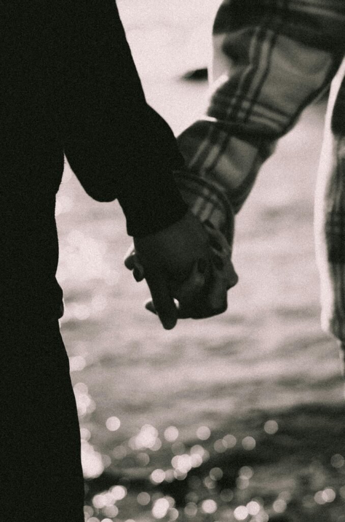 A touching moment of a couple holding hands in a black and white setting, symbolizing love and connection.